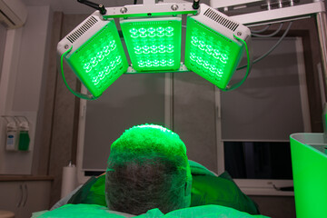 Young woman having LED light facial treatment in beauty salon