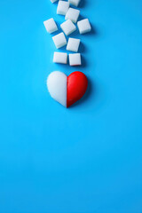 Red heart and sugar cubes symbolizing diabetes awareness on blue background with copy space for World Diabetes Day November 14