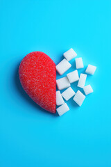 Red heart and sugar cubes symbolizing diabetes awareness on blue background with copy space for World Diabetes Day November 14