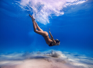young fit woman diving into the blue sea
