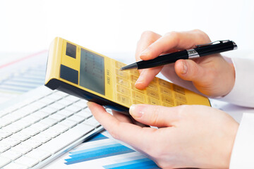 A woman works with a calculator on an annual report in the office. Close-up