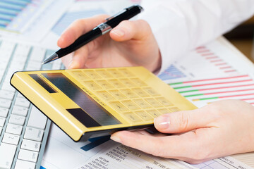 A woman works with a calculator on an annual report in the office. Close-up