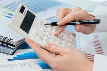 A woman works with a calculator on an annual report in the office. Close-up