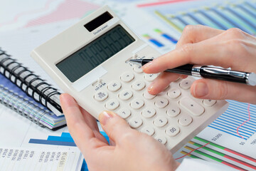 A woman works with a calculator on an annual report in the office. Close-up