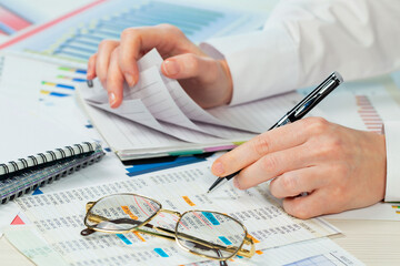 A woman works with business papers, on a report. Close-up of her hands.