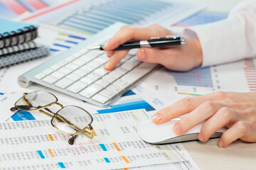 A woman working on an accounting report with a computer. Close-up of her hands.