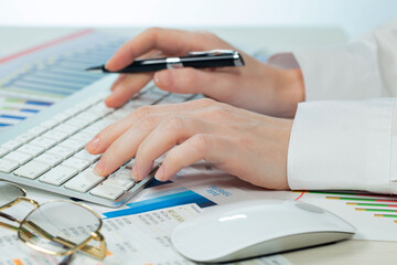 A woman working on an accounting report with a computer. Close-up of her hands.
