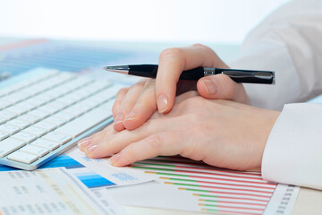 A woman working on an accounting report with a computer. Close-up of her hands.