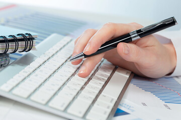 A woman working on an accounting report with a computer. Close-up of her hands.