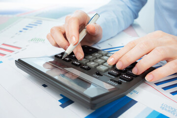A woman works with a calculator on an annual report in the office. Close-up