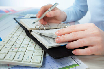 A woman works with business papers, on a report. Close-up of her hands.