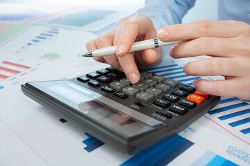 A woman works with a calculator on an annual report in the office. Close-up