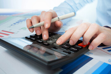 A woman works with a calculator on an annual report in the office. Close-up