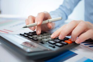 A woman works with a calculator on an annual report in the office. Close-up