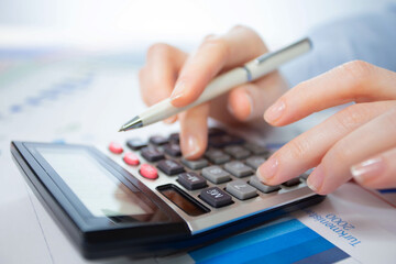 A woman works with a calculator on an annual report in the office. Close-up