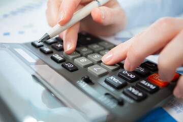 A woman works with a calculator on an annual report in the office. Close-up