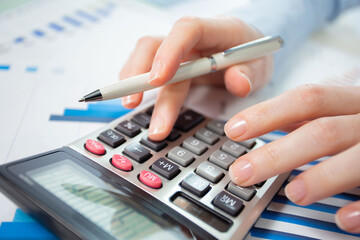 A woman works with a calculator on an annual report in the office. Close-up