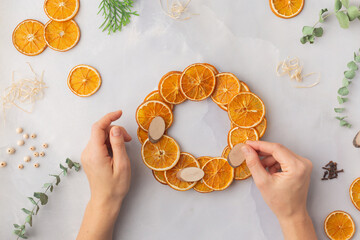 A decorative wreath crafted from dried orange slices, eucalyptus leaves, dried cloves, wooden cuts step by step instruction diy