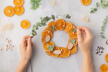 A decorative wreath crafted from dried orange slices, eucalyptus leaves, dried cloves, wooden cuts step by step instruction diy