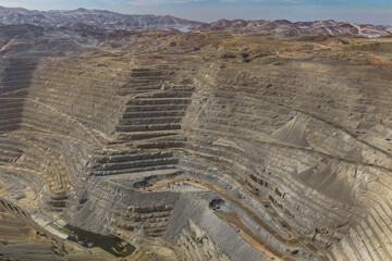 Aerial view of an open-pit mine with mineral transport dump trucks in transit