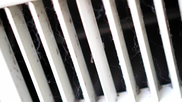Close-Up View of Air Vent with Dust and Cobwebs.