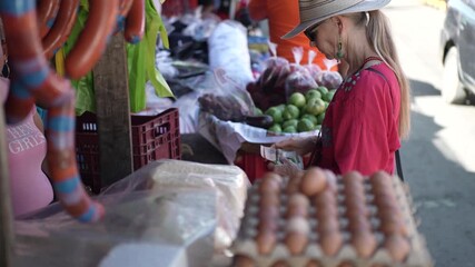 Mature woman shops at street markets in Granada Nicaragua, looking for fresh food and local items among various stalls and vendors.