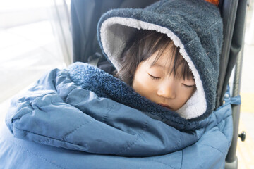 ベビーカーの寝袋に包まれた日本人の女の子の幼児