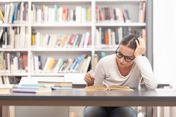 Stressed Female University Student Studying at Library Desk