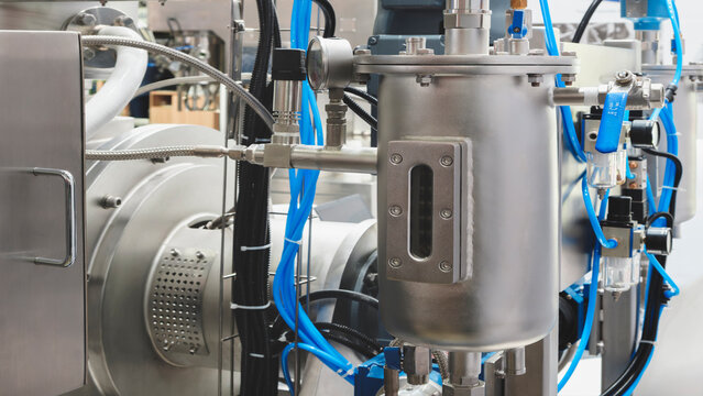 Large industrial machine in pharmaceutical factory with many stainless steel pipes, taps and other parts, industrial pharmaceutical concept
