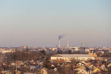 Buildings and smoke stacks are seen in a city landscape as sunlight begins to rise in the morning sky over the area