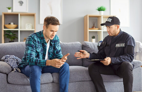 Portrait of police man officer talking to witnesses making interview sitting with young man robbery victim after burglary interrogating him at home. Crime, robbery, safety of property concept.