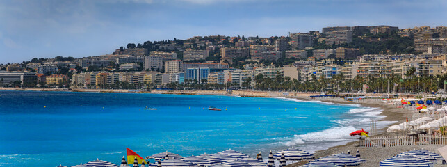 Pebble beach with beach umbrellas and chairs on Mediterranean Sea in Nice France