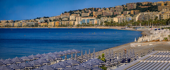 Striped umbrellas line a beach with turquoise Mediterranean waters, Nice, France