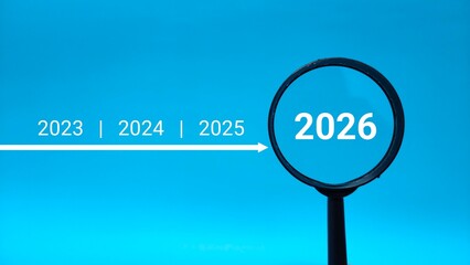 2026 inside of Magnifying glass on blue background. Focus current year, achievement, target concept
