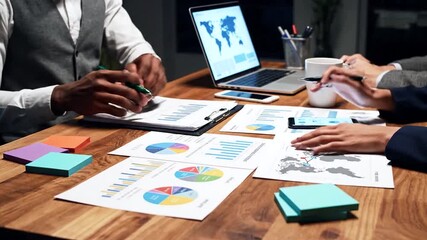 Close-up of a diverse business team (adult man and woman) collaborating, analyzing financial data, graphs, and charts on paper reports and a laptop screen during a professional meeting. - Powered by Adobe
