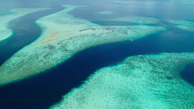Aerial shot descending towards small boats anchored in tropical coral reef conservation area