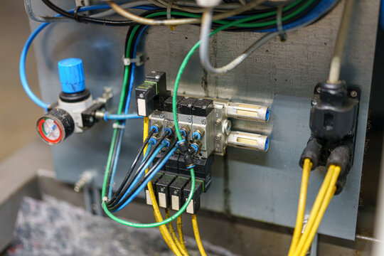 Close-up view of wiring and components on a machine in an industrial setting, showing connections and controls for operation