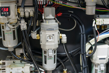 Equipment and components in a machine control panel during maintenance at a manufacturing facility in the afternoon