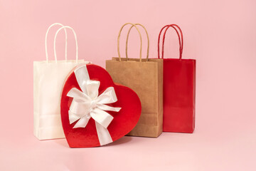A festive backdrop with heart-shaped cardboard boxes with bows and gift bags on a pink background. Congratulations for holidays, Mother's Day, weddings, and Valentine's Day