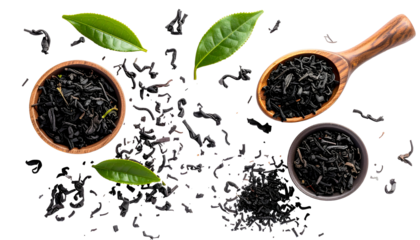 Overhead view of tea leaves, bowls, spoon, and fresh green leaves, scattered on black