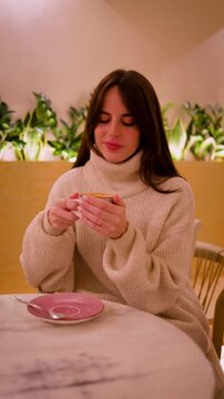 Young woman in a cozy cafe drinking cappuccino