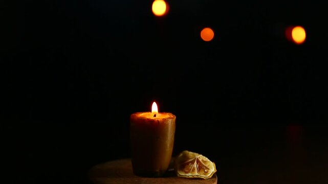 Bees wax candle burning light on wooden candlestick for mood, relaxation, meditation dark black background with many bright lights. Atmosphere mood decoration with homemade single candle flame