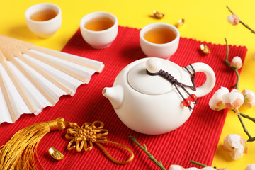 Traditional tea with paper fan and Chinese symbols on yellow background