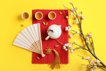 Traditional tea with paper fan and Chinese symbols on yellow background