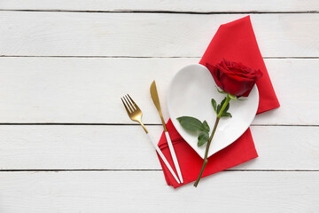 Table setting for Valentine's Day with rose flower on white wooden background