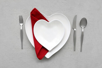 Table setting for Valentine's Day with heart-shaped plates on grey grunge background
