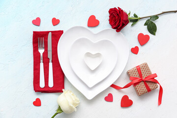 Table setting for Valentine's Day with rose flowers, gift box and decorative hearts on blue grunge...