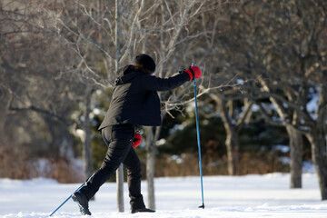 Une femme pratique le ski de fond dans un parc en hiver.