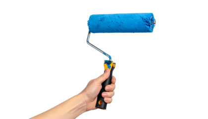 Hand holding a paint roller with a blue nap, isolated on a black background