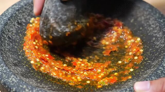Close up of chili paste preparation in stone mortar for culinary use